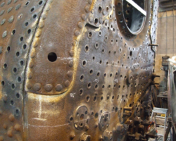 Work well on its way in drilling out all rivets and stays securing those parts of the firebox to be replaced by new metal, including two thirds of the backplate, seen here at the bottom of the picture since the boiler is inverted.