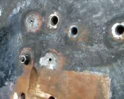 All stretchers attaching to the area have to be removed, a process involving drilling and burning out the rivets. This shows some ground flat. Drilled through and others completely removed. Bolts and nuts have been inserted in some holes to support the structure until this task is complete.