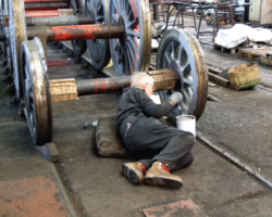 Meanwhile, another member of the team applies primer to the pony truck wheels.