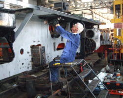 A Fund working party member attacks the new steel with a rotary wire brush, in preparation for its coat of paint.