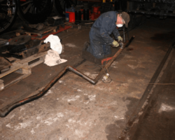 Our Engineering Manager John Bowater uses the angle grinder and wire brush to clean up part of the vacuum brake pipework that runs under the Left hand running plate.