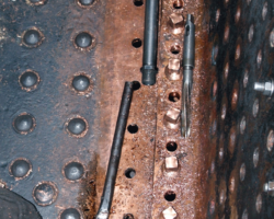 The view vertically downwards towards the crown with the backplate to the right, and patch screws in course of being fitted. Note the boilersmith’s tools, including a large spanner (bottom) and reamer (right).