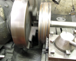 The piston turning in the lathe, with the cutting tool engaging the right hand groove.