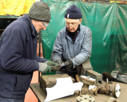 John A and Fraser cut a gasket for the gauge frames in the foreground.
