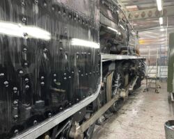 The loco’s boiler cladding has already received two coats of paint whilst the newly rubbed down and thus  white looking valancing looks to be ready for its turn from the paintbrush. The cab side nearest the camera appears to have some early rubbing down underway.